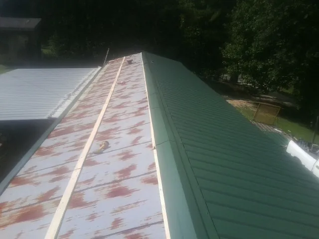 Old rusted panels beside newly installed green metal roofing — Wind Damage Roof Repair by Roofing Brothers in Broomfield