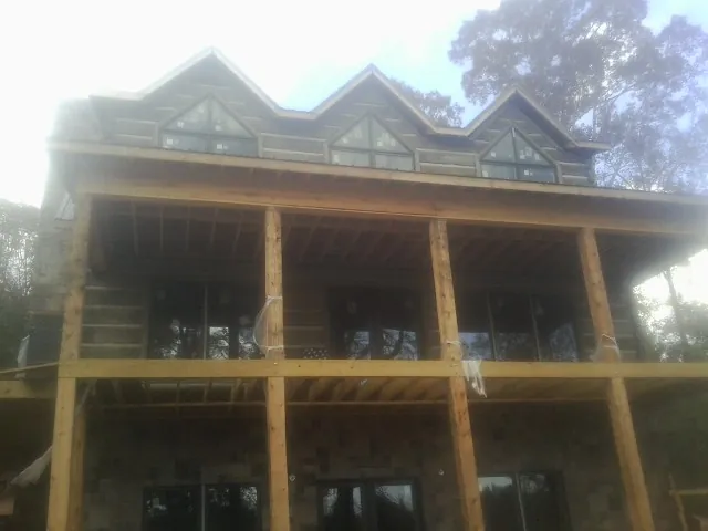 Dormers and porch framing on a large log home under construction — Roof Coating work by our crew in Broomfield