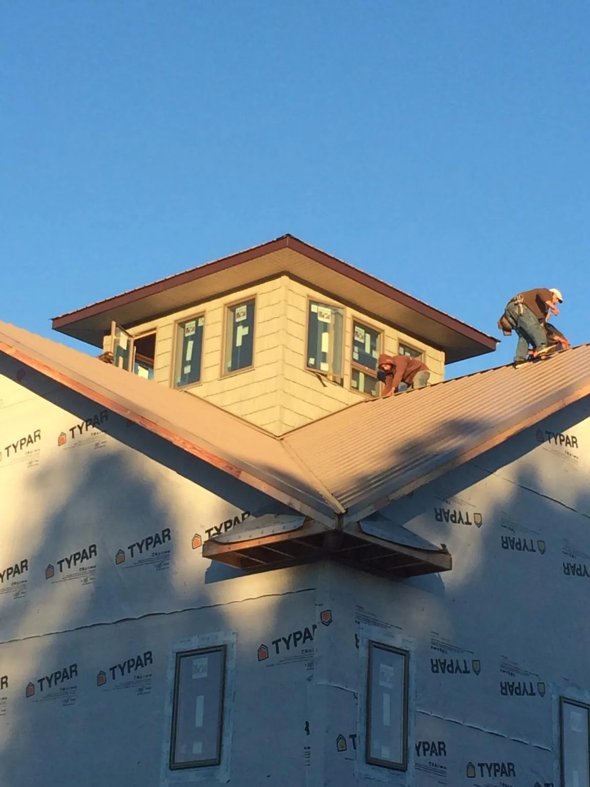 Roofers working around a rooftop cupola on a new metal roof at sunset — Roof Waterproofing in Broomfield by Roofing Brothers